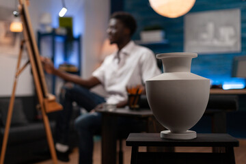 African american artist creating professional sketch of ceramic vase on easel in modern art studio. Drawing student creating pencil masterpiece on canvas in home crafts studio at bedroom.
