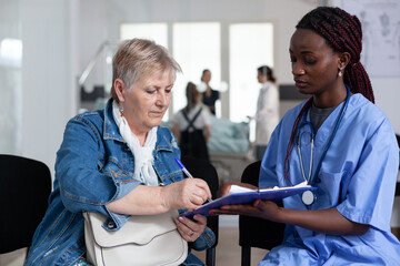 African american female geriatrician discharging elderly patient from clinic. Senior woman forming...
