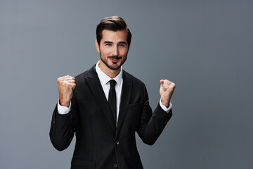 Man business in a suit happy smile with teeth raised hands up clenched fists on a gray background. The joy of winning in business