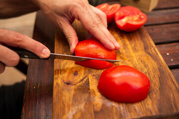 person cutting tomatoes in julienne on a wood