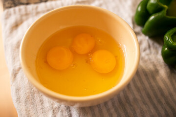 egg whites and yolks seasoned inside a ceramic container on a wood