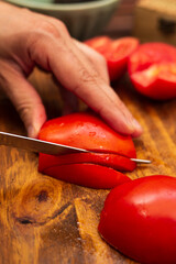 person cutting tomatoes in julienne on a wood