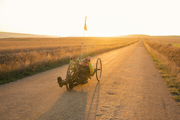 Scenic Shot of a Young Man Athlete with disability Riding a Handcycle. Adaptive Exercise Outdoors at Sunset . High quality photography.