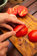 person cutting tomatoes in julienne on a wood