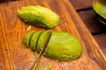 Avocado peeled and sliced on top of a wooden table