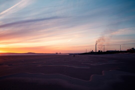 Beautiful view of a sandy beach with steel works pollution at sunset