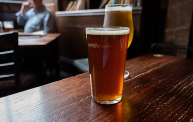 Pint glasses of british ale and lager beer served in old vintage English pub