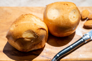 Italian yellow smoked cheese scamorza served on olive tree wooden plank
