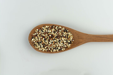 quinoa seed mix in a wooden spoon on white background isolated top view