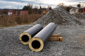 Cut pipes with thermal insulation lie on the construction site.