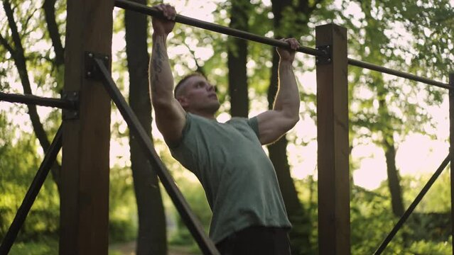 Young man finishing with push ups and resting in the outdoor park. Healthy lifestyle concept. Slow motion.