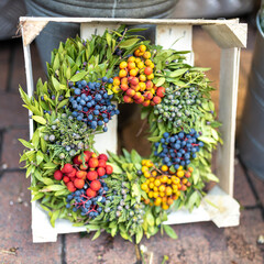 Christmas fir tree wreath decorated with artificial flowers and tangerine in the box