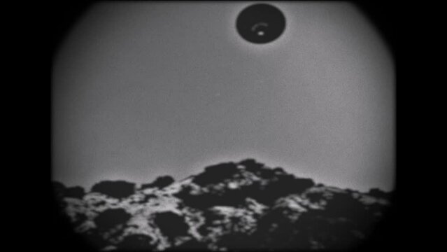 KINESCOPE LOOKING FOOTAGE A UFO FLYING OVER A MOUNTAIN.  BLACK AND WHITE IN FULL HD.