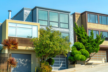 Bright row of modern houses in sunlight with trees in yard and blue sky