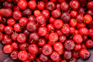 Fresh organic cherry acerolas close-up forming a background pattern.