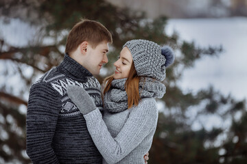 Obraz premium The couple hugs and smiles while standing in the snow.