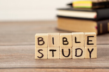 Bible study text on wood cubes on rustic table with Holy Bible, notebook, and pen in the background. A closeup.