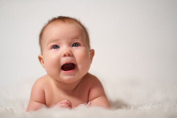 Portrait of an infant on a white background with a cheerful expression of emotion