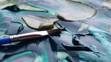 Brush on artist's palette with mixed paints, closeup