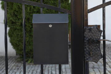 Black metal letter box on fence outdoors