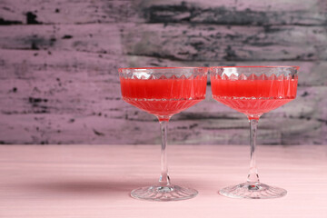 Cocktail glasses of delicious fresh watermelon juice on light wooden table. Space for text