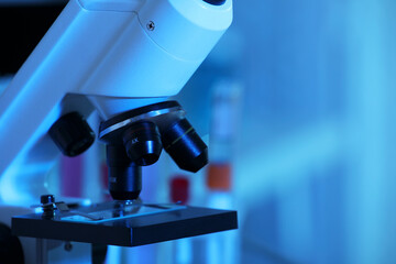 Closeup view of modern microscope with glass slide in laboratory, toned in blue. Space for text
