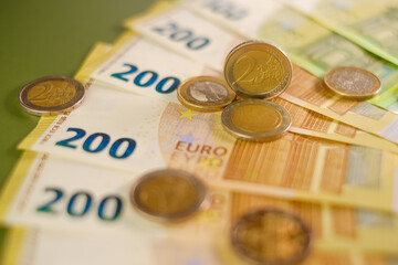  euro coins and Two hundred euro banknotes on a dark green background.Expenses and incomes in...