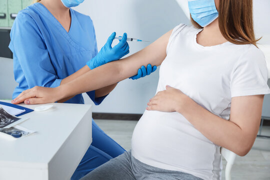 Doctor giving injection to pregnant woman in hospital, closeup