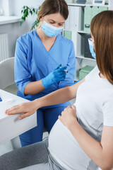 Doctor giving injection to pregnant woman in hospital