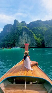 Thai women in front of a Longtail boat at Pileh Lagoon with the green emerald ocean at Koh Phi Phi Thailand,