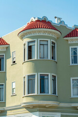 Cylindrical turret or tower in modern building with red stone roof tiles and beige stucco exterior with bay windows on modern home or apartment building