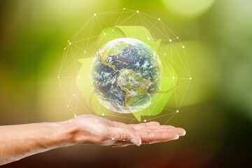 Hands hold Earth globe on nature background.