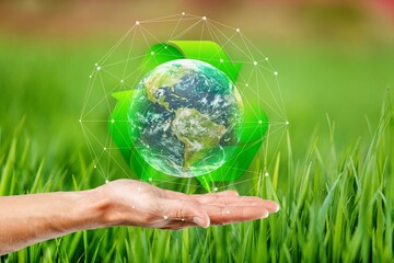 Hands hold Earth globe on nature background.