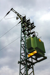 Green power pole on dark gloomy clouds background in Germany.