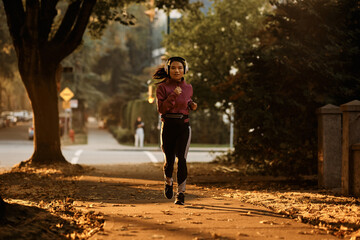 Full length of Asian female athlete jogging on street.