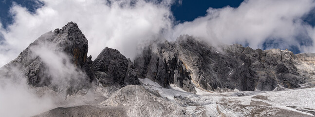 Panorama of Jade Dragon Snow Mountain with blue sky and clouds creating gorgeous view. Landscape of beautiful nature of Jade Dragon Snow Mountain in China.