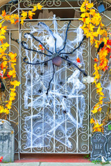 Security gate near front door in yard with halloween decorations with spiders and webs and tombstones in the shade during holidays