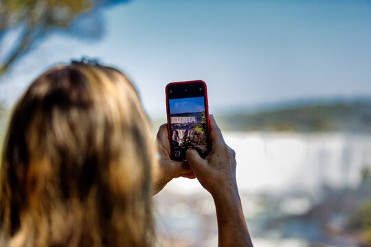 Woman takes a picture of the Iguazu Falls