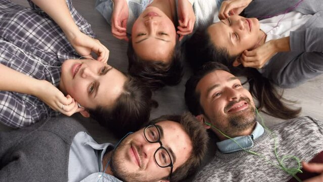 Collaboration, music and relax with a business team lying on the floor of their office together from above. Teamwork, friends and team building with a man and woman employee group resting at work