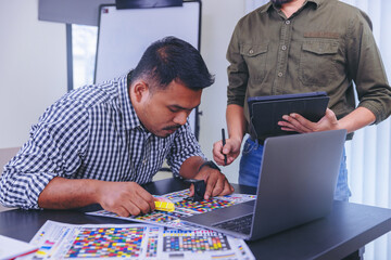 Crop image of worker checking print quality of media graphics proof print in printing industry....