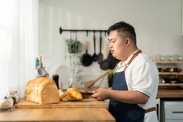 Asian young man with down syndrome baking bakery in kitchen at home. 