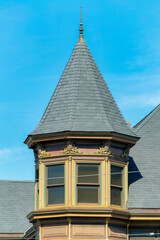 Exterior turret or spire with beige stucco home or house and gray slatted roof with spike on pinacle © Aaron