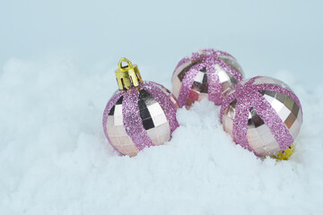 Obraz na płótnie Canvas Pink Glittered Christmas baubles lying in the snow.