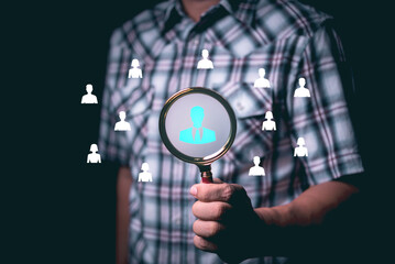 Male hand holding magnifying glass with portrait icon showing searching for talented personnel to help