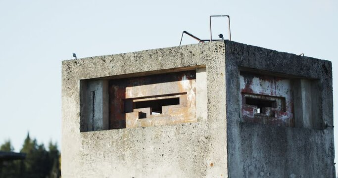 Closeup of a machine gun pill box with trees in the background.