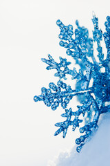 Glittery blue snowflake ornament in real fresh snow after a winter snow storm with space for text