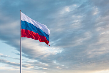 Waving Russian flag against a blue sky with clouds and empty space for text. Room for text.