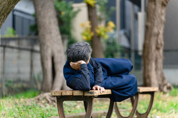 Fototapeta premium 公園のベンチで寝るシニア男性