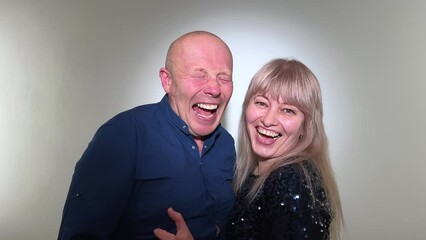 Joy happiness success funny comedy Loud sincere laughter man and woman in blue looking at the camera They open their mouths wide and laugh then look at each other and talk slow motion adults 50-55