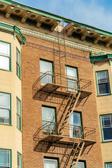 Modern brown stone facade on outside of house with black metal fire escape ladder for saftey from disasters